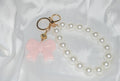 Chaveiro Rosé Pearl Bow — chaveiro com pérolas e laço rosa.