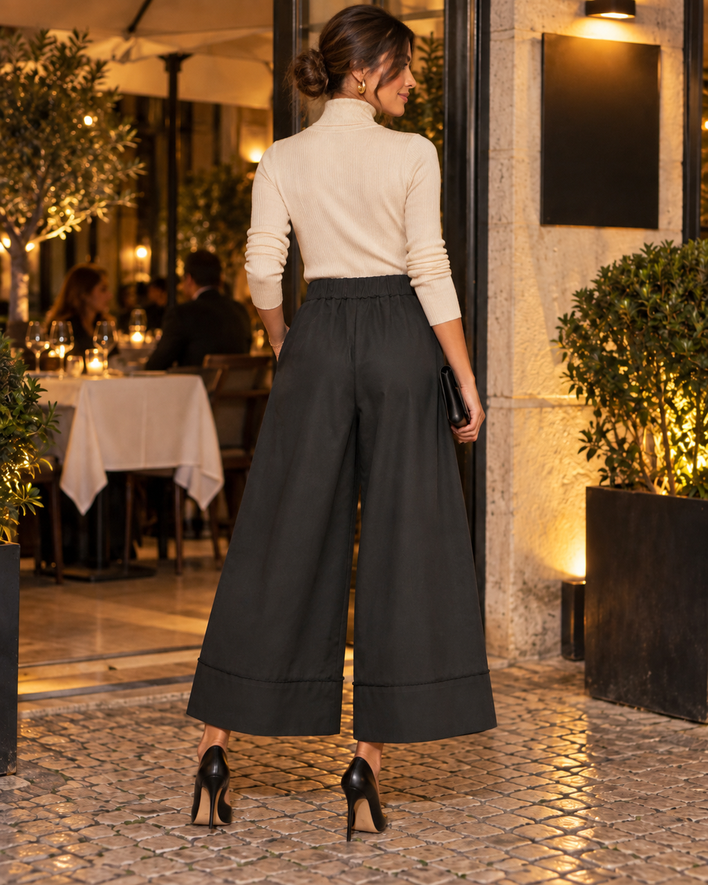 Calças culotte pretas de perna larga, vista de costas com modelo e sapatos de salto alto