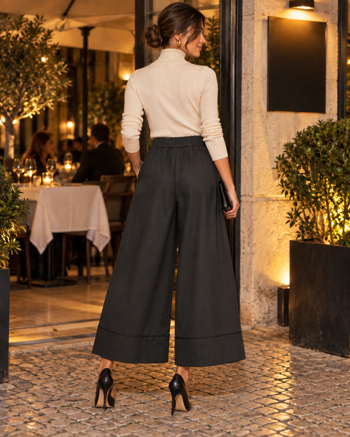 Calças culotte pretas de perna larga, vista de costas com modelo e sapatos de salto alto