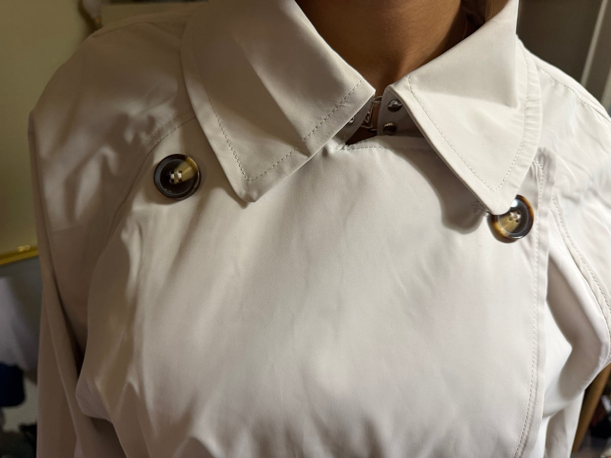 Detalhe do cinto com fivela e botões da gabardina longa creme