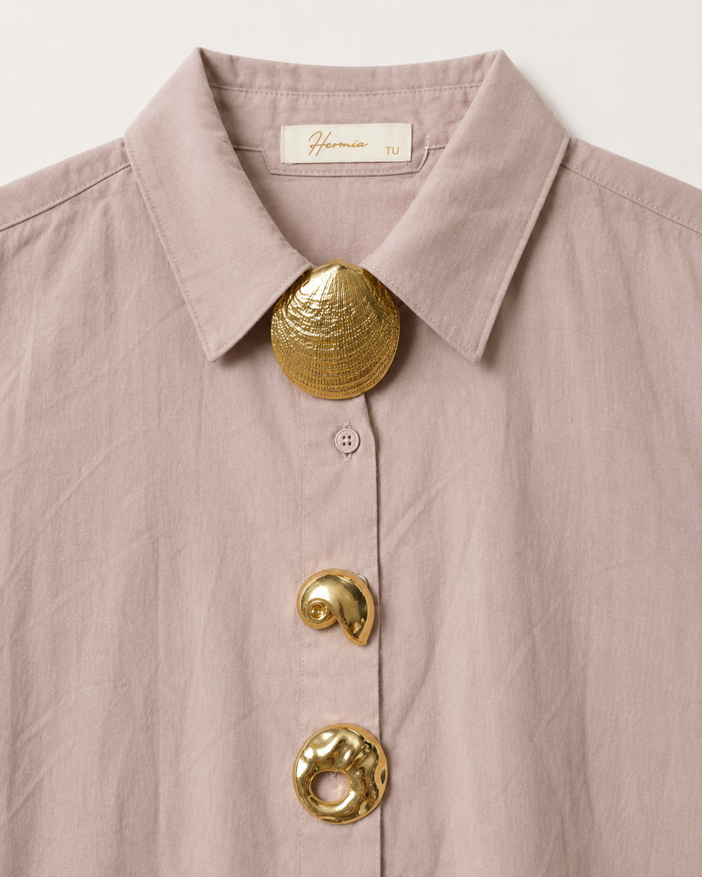 Detalhe dos três adornos dourados da camisa rosa velho