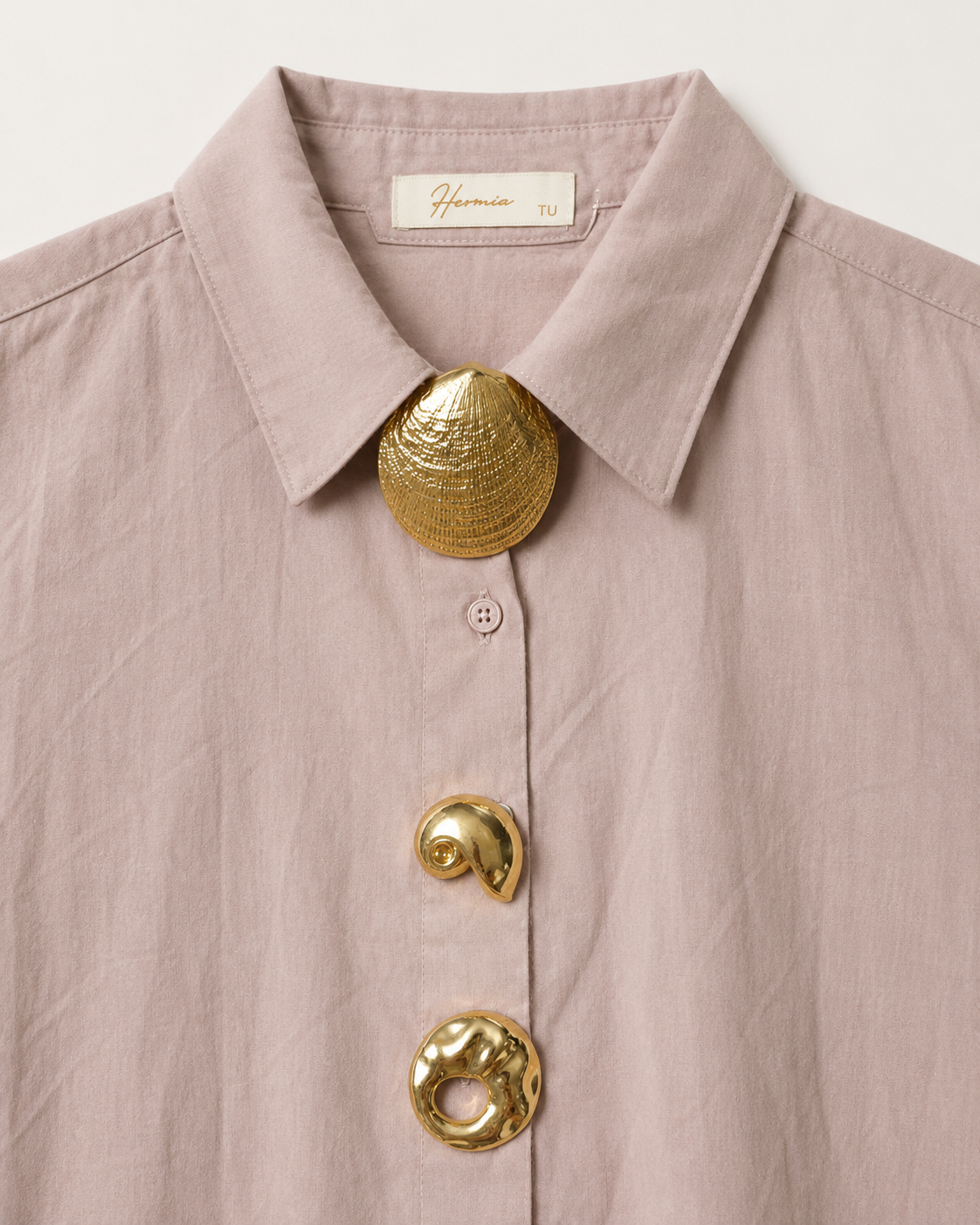 Detalhe dos três adornos dourados da camisa rosa velho