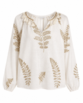 Blusa cru em tecido leve com bordado dourado de folhas e pompons na gola, vista de frente