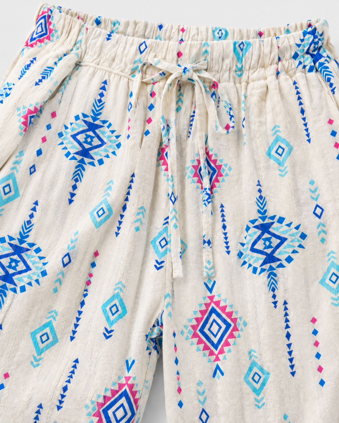 Detalhe do cós elástico com cordão e do estampado ikat azul sobre fundo branco